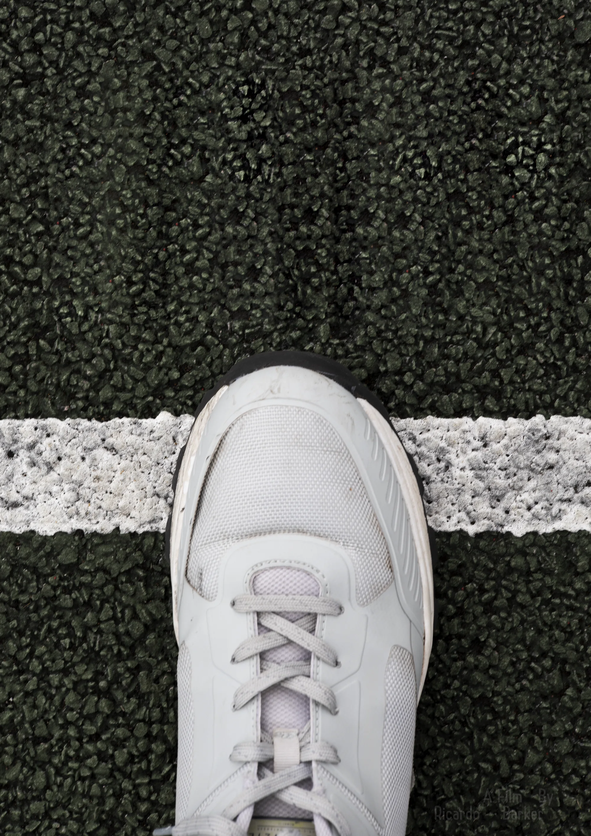 Where Is The Line: a white trainer steps onto a white line painted across black asphalt